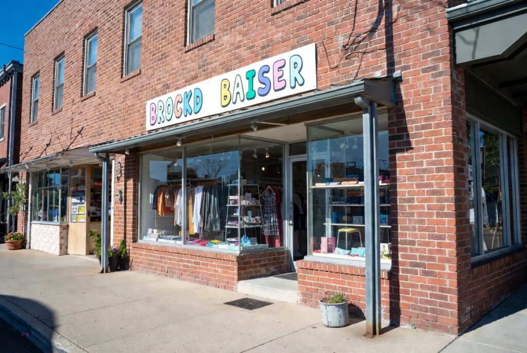 rick building storefront of Brockd Baiser shop with colorful sign and clothing display in windows