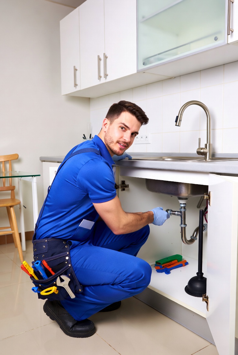 plumber repairing kitchen sink pipe with tool belt